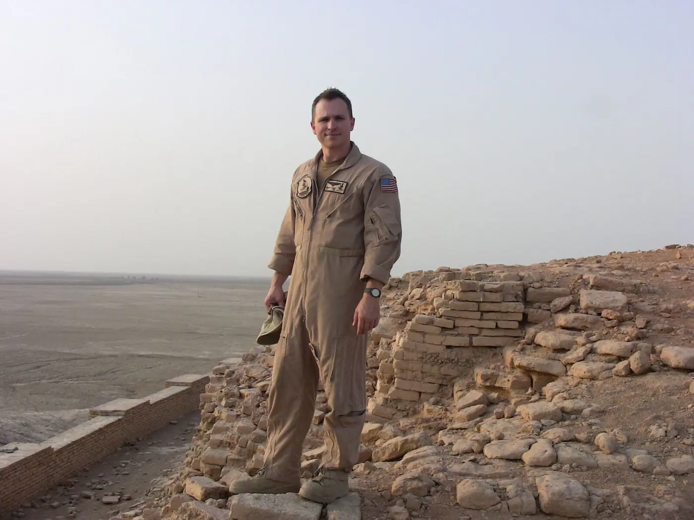 Brian Vinci on deployment in the Middle East, standing in a tan flight suit near desert ruins
